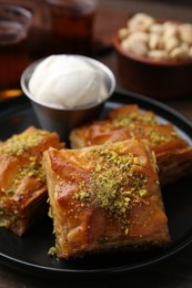 Photo of Delicious baklava with crushed nuts and ice cream on table, closeup