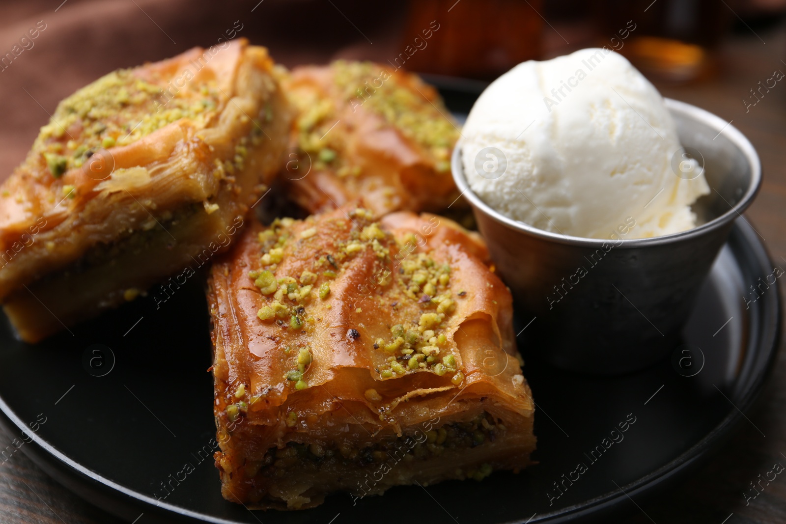 Photo of Delicious baklava with crushed nuts and ice cream on table, closeup