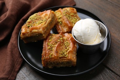 Delicious baklava with crushed nuts and ice cream on wooden table, closeup