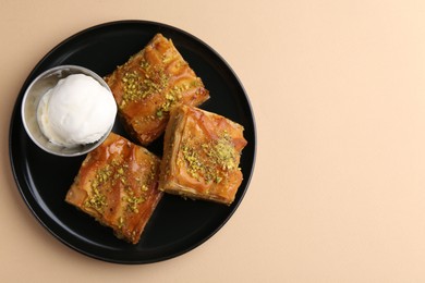 Photo of Delicious baklava with crushed nuts and ice cream on beige table, top view. Space for text