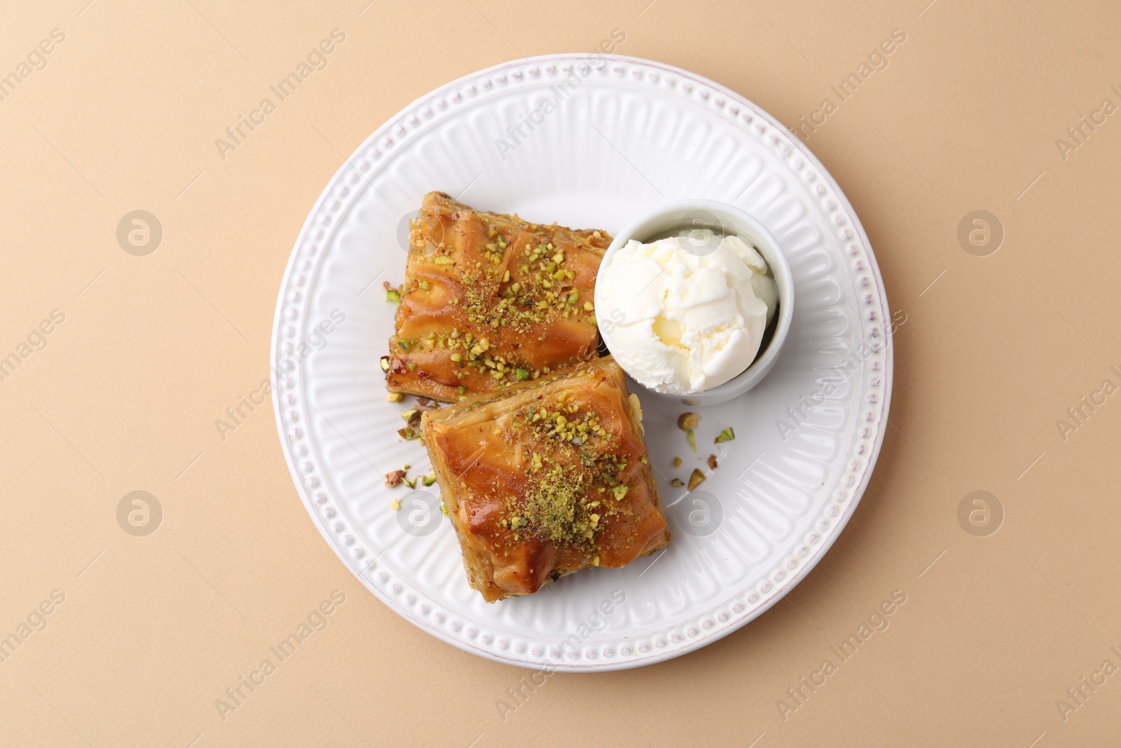Delicious baklava with crushed nuts and ice cream on beige table, top view Photo of Delicious baklava with crushed nuts and ice cream on beige table, top view