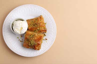 Photo of Delicious baklava with crushed nuts and ice cream on beige table, top view. Space for text