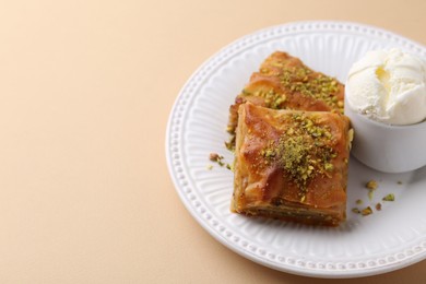 Photo of Delicious baklava with crushed nuts and ice cream on beige table, closeup. Space for text