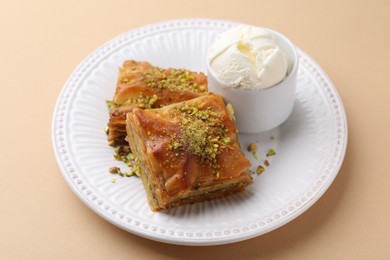 Photo of Delicious baklava with crushed nuts and ice cream on beige table, closeup