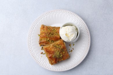 Photo of Delicious baklava with crushed nuts and ice cream on grey table, top view