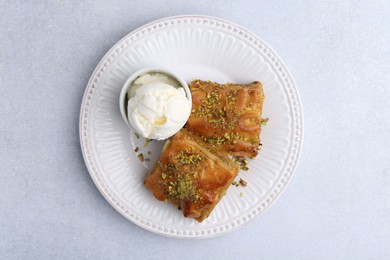 Photo of Delicious baklava with crushed nuts and ice cream on grey table, top view