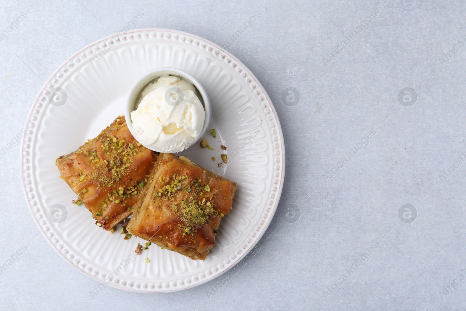 Photo of Delicious baklava with crushed nuts and ice cream on grey table, top view. Space for text