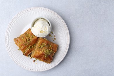 Photo of Delicious baklava with crushed nuts and ice cream on grey table, top view. Space for text