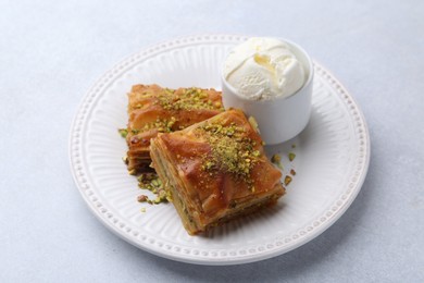 Photo of Delicious baklava with crushed nuts and ice cream on grey table, closeup