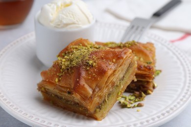 Photo of Delicious baklava with crushed nuts and ice cream on grey table, closeup