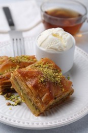 Photo of Delicious baklava with crushed nuts and ice cream on grey table, closeup