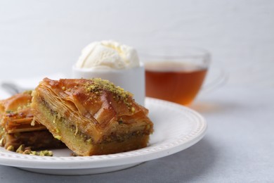 Photo of Delicious baklava with crushed nuts and ice cream on grey table, closeup. Space for text