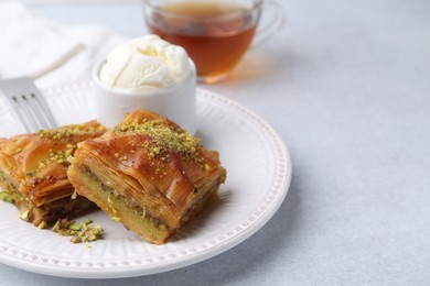 Photo of Delicious baklava with crushed nuts and ice cream on grey table, closeup. Space for text