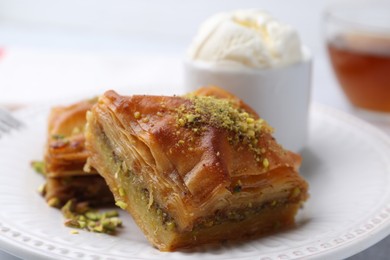 Photo of Delicious baklava with crushed nuts and ice cream on table, closeup