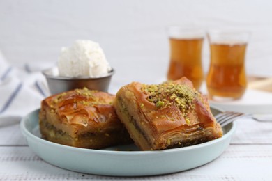 Photo of Delicious baklava with crushed nuts and ice cream on white wooden table, closeup