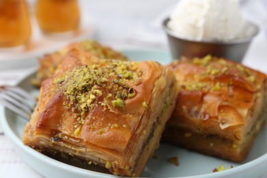 Delicious baklava with crushed nuts and ice cream on table, closeup