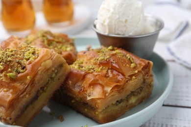 Photo of Delicious baklava with crushed nuts and ice cream on white wooden table, closeup