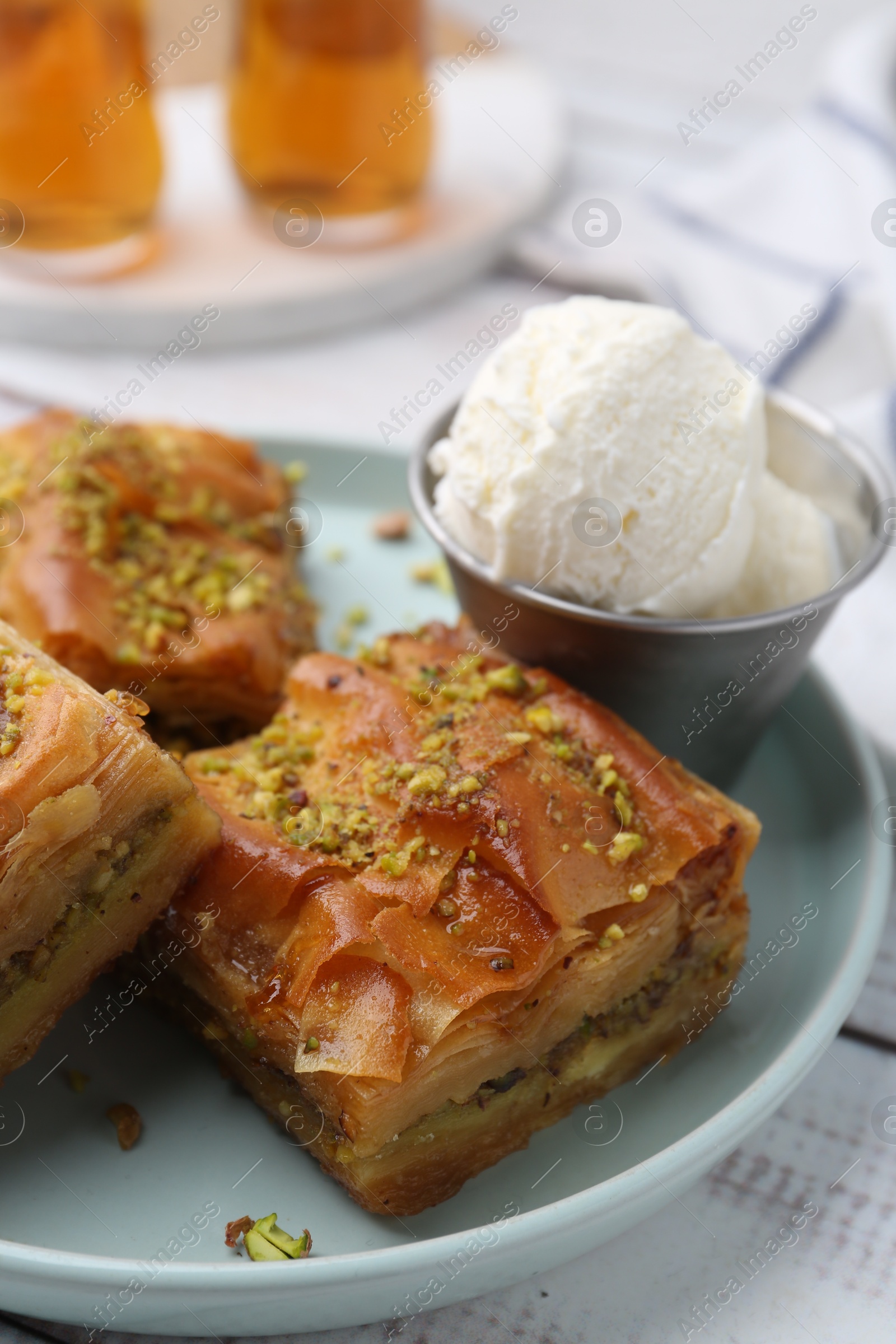 Photo of Delicious baklava with crushed nuts and ice cream on white wooden table, closeup