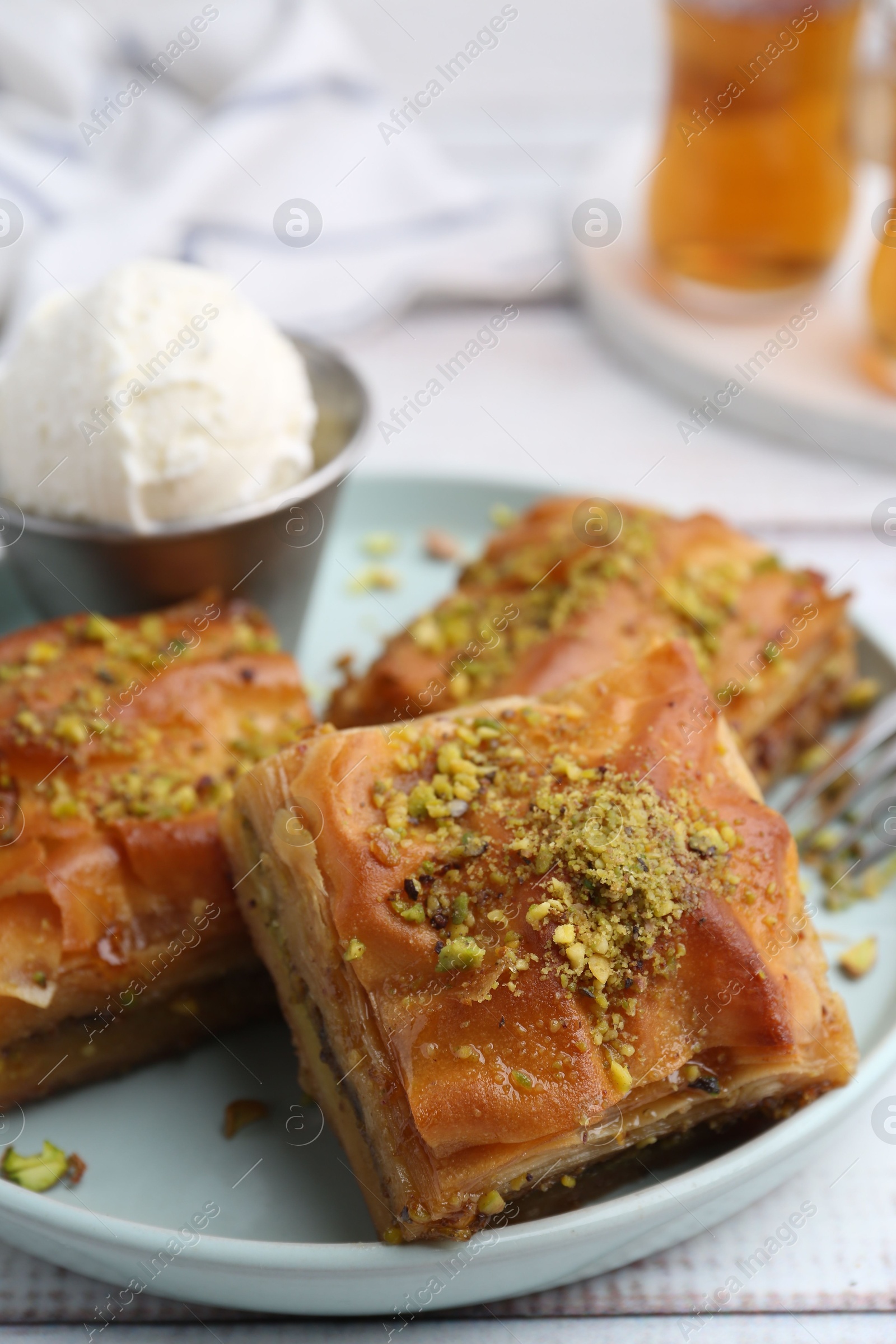 Delicious baklava with crushed nuts and ice cream on white wooden table, closeup Photo of Delicious baklava with crushed nuts and ice cream on white wooden table, closeup