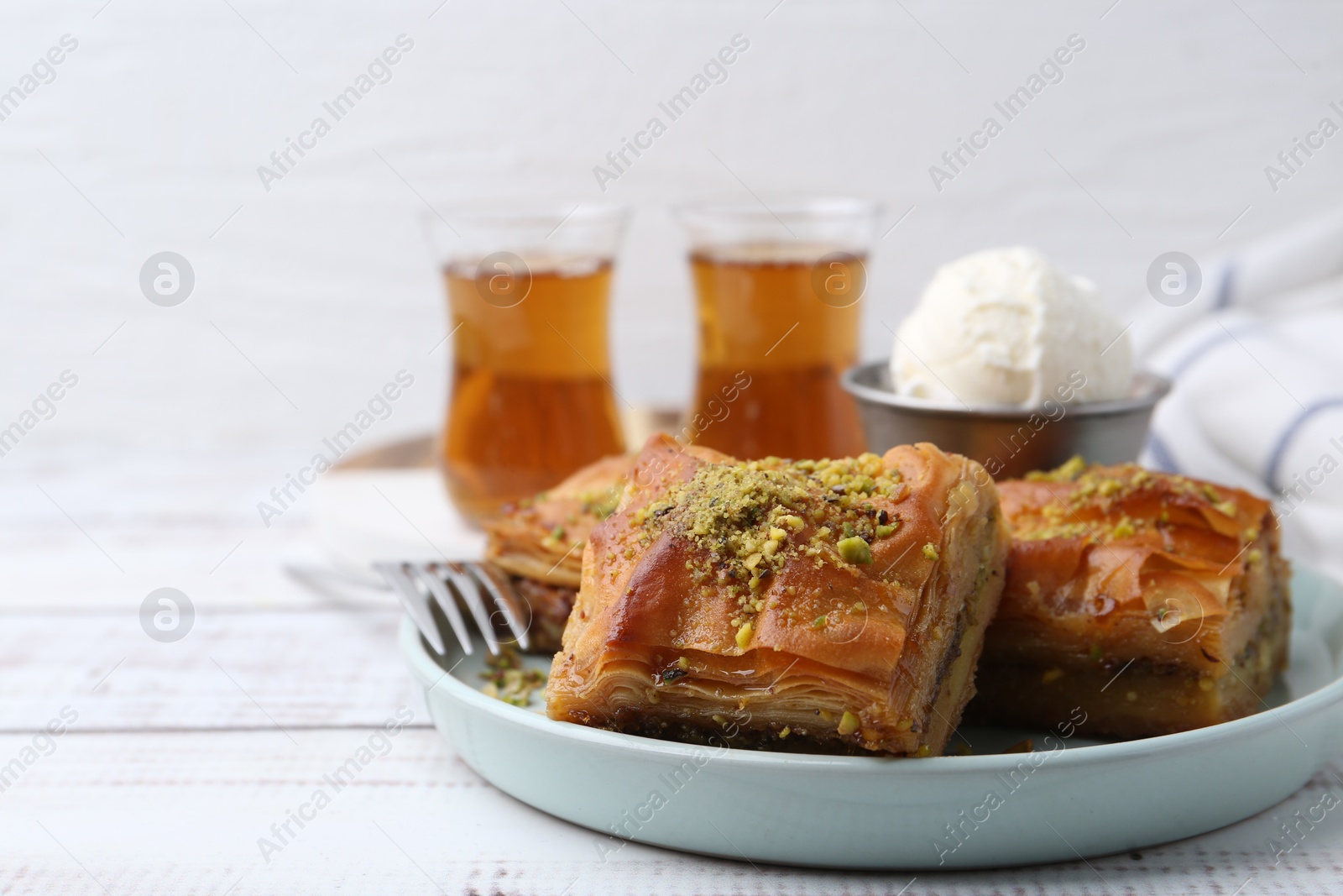 Delicious baklava with crushed nuts and ice cream on white wooden table, closeup. Space for text Photo of Delicious baklava with crushed nuts and ice cream on white wooden table, closeup. Space for text