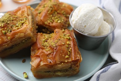 Photo of Delicious baklava with crushed nuts and ice cream on table, closeup