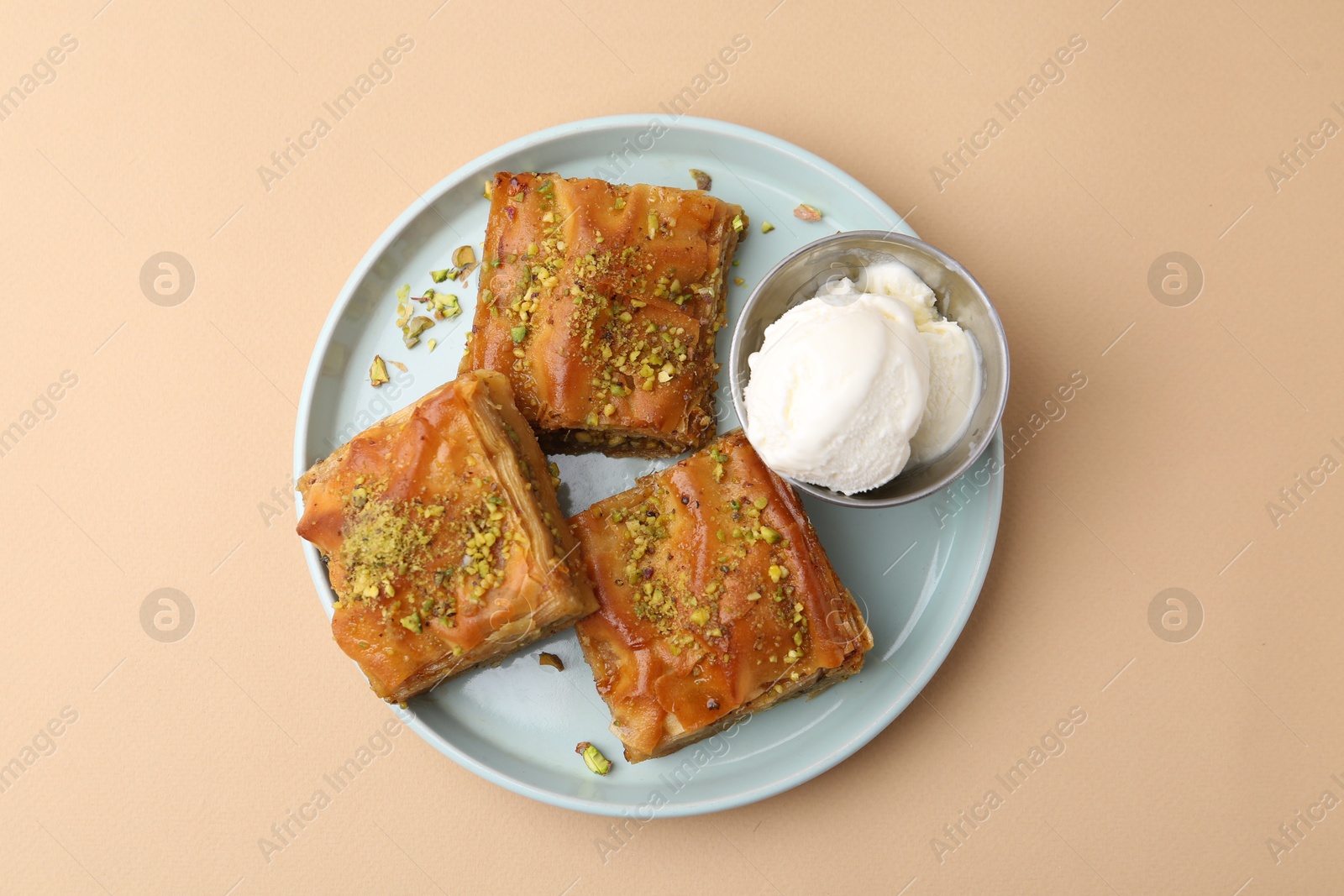 Delicious baklava with crushed nuts and ice cream on beige table, top view Photo of Delicious baklava with crushed nuts and ice cream on beige table, top view