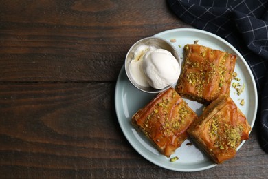 Delicious baklava with crushed nuts and ice cream on wooden table, top view. Space for text