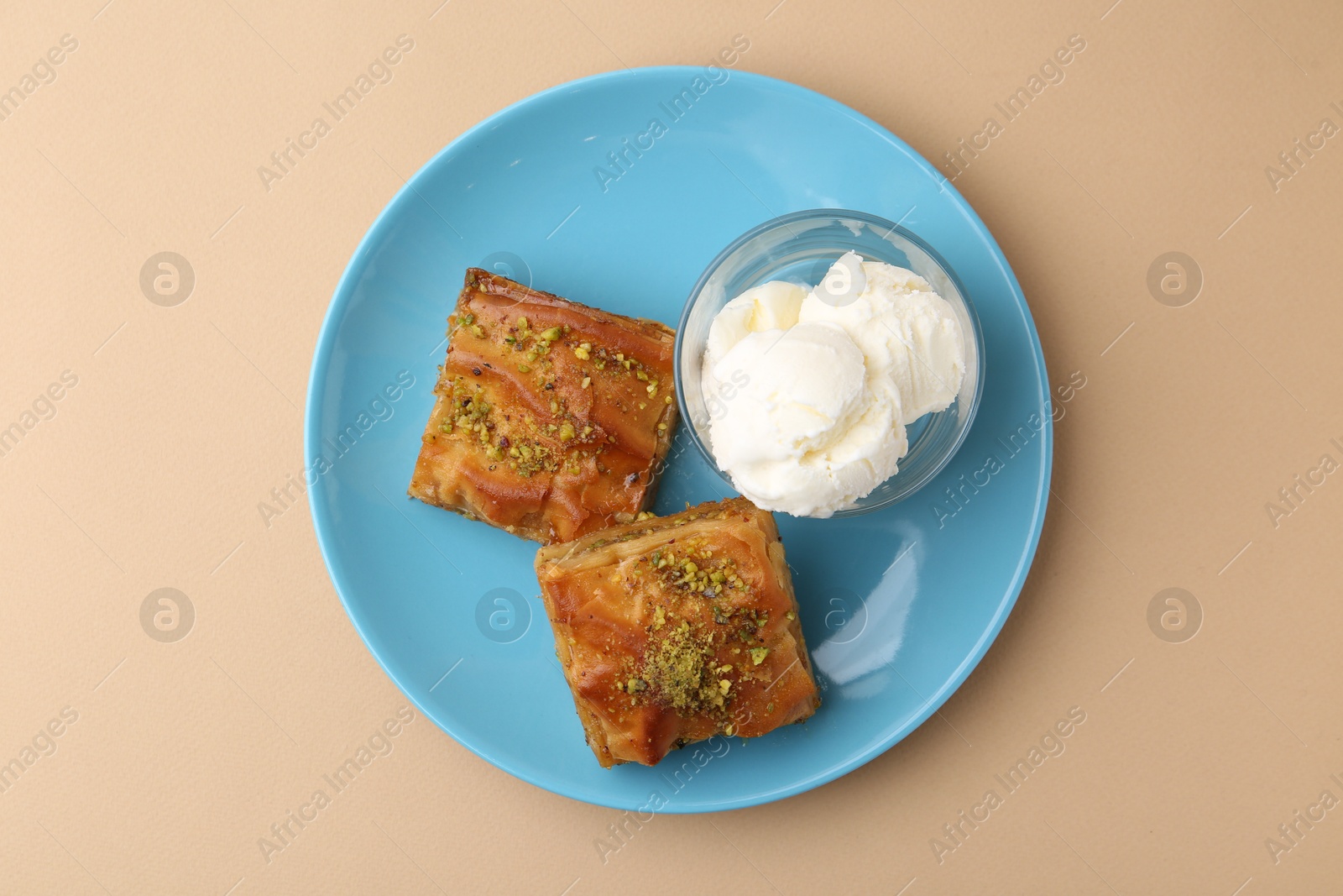 Photo of Tasty baklava with chopped nuts and scoops of ice cream on beige table, top view