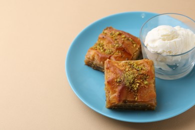 Photo of Tasty baklava with chopped nuts and scoops of ice cream on beige table, closeup. Space for text