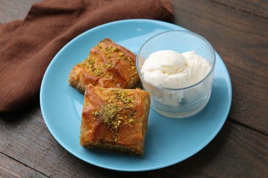 Photo of Tasty baklava with chopped nuts and scoops of ice cream on wooden table, closeup