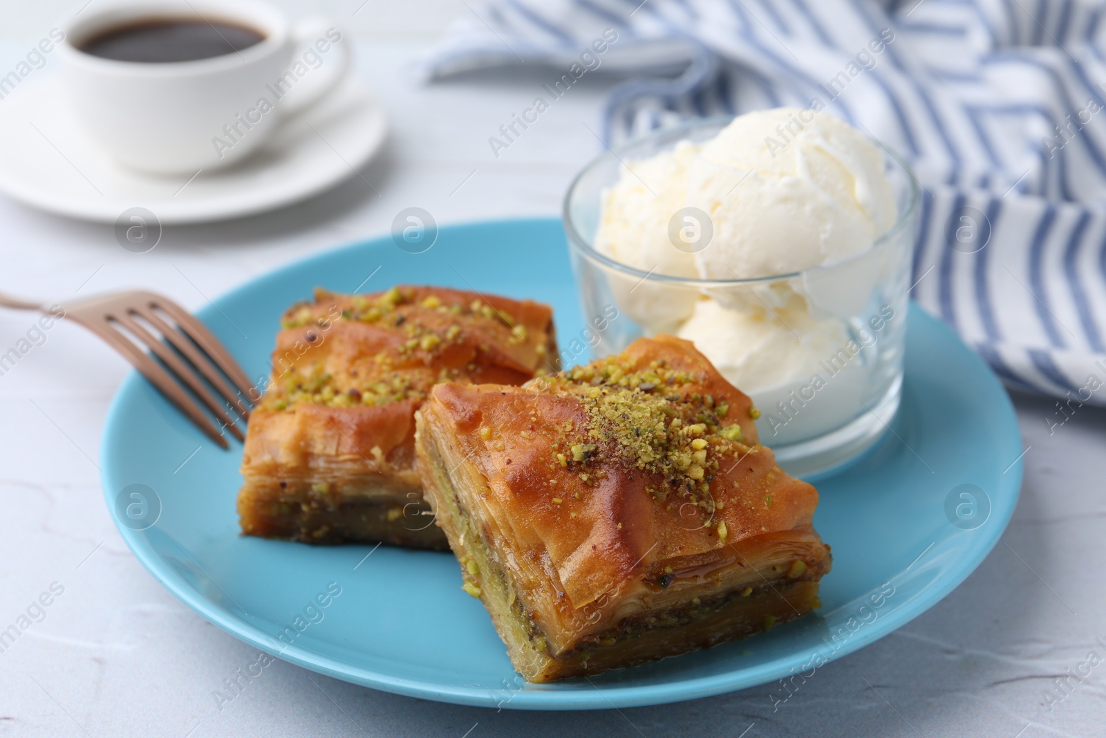 Photo of Tasty baklava with chopped nuts and scoops of ice cream on white table, closeup