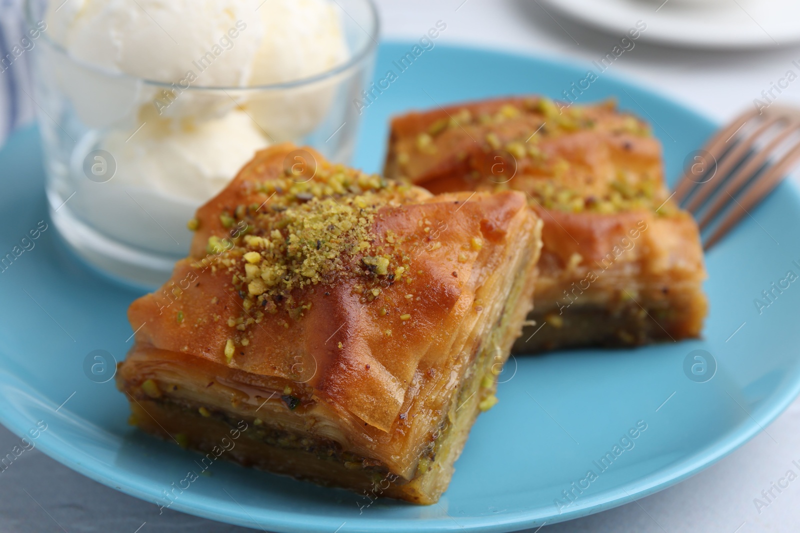 Photo of Tasty baklava with chopped nuts and scoops of ice cream on table, closeup