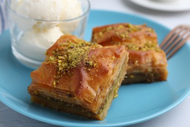 Photo of Tasty baklava with chopped nuts and scoops of ice cream on table, closeup