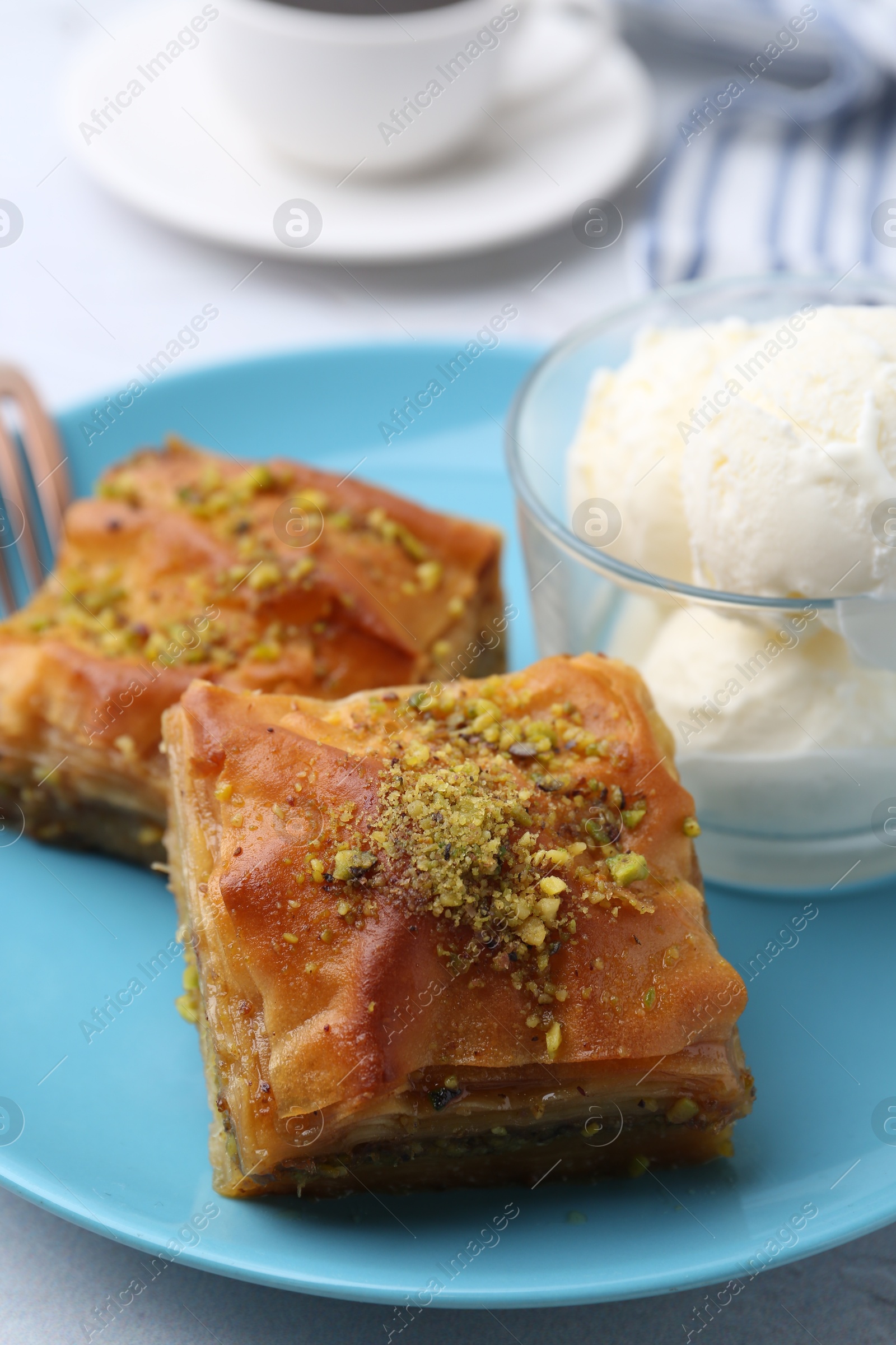 Photo of Tasty baklava with chopped nuts and scoops of ice cream on table, closeup