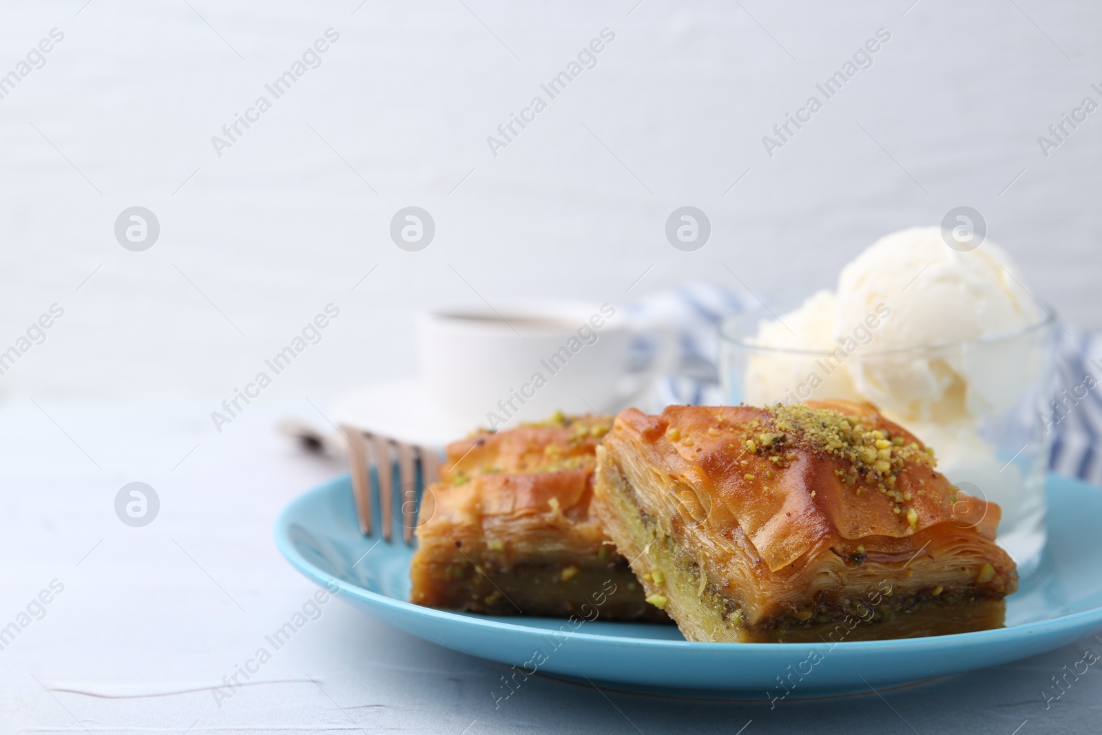 Photo of Tasty baklava with chopped nuts and scoops of ice cream on white table, closeup