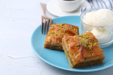 Photo of Tasty baklava with chopped nuts and scoops of ice cream on white table, closeup. Space for text