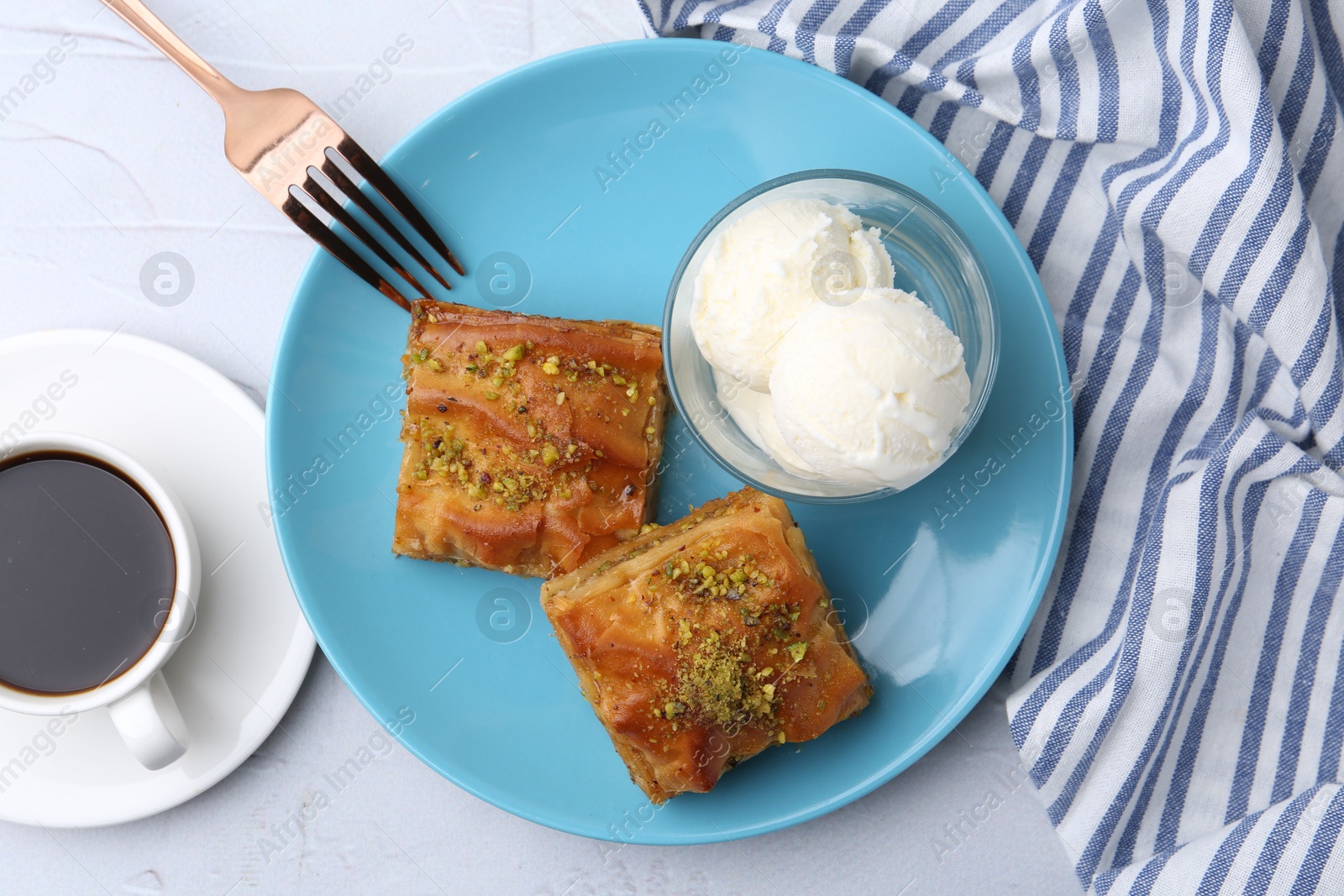 Photo of Tasty baklava with chopped nuts, scoops of ice cream and coffee on white table, flat lay