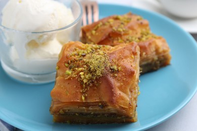 Photo of Tasty baklava with chopped nuts and scoops of ice cream on table, closeup