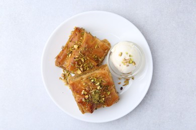 Photo of Tasty baklava with chopped nuts and scoop of ice cream on light grey table, top view