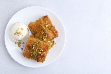 Tasty baklava with chopped nuts and scoop of ice cream on light grey table, top view. Space for text