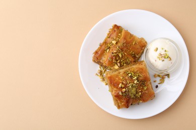 Tasty baklava with chopped nuts and scoop of ice cream on beige table, top view. Space for text