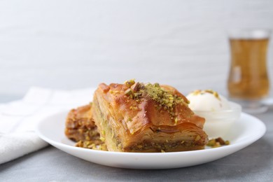 Photo of Tasty baklava with chopped nuts and scoop of ice cream on grey table, closeup