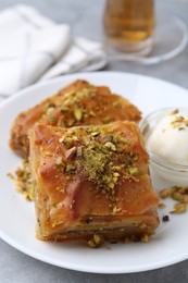 Photo of Tasty baklava with chopped nuts and scoop of ice cream on grey table, closeup