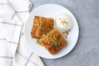 Photo of Tasty baklava with chopped nuts and scoop of ice cream on grey table, top view