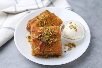 Photo of Tasty baklava with chopped nuts and scoop of ice cream on grey table, closeup