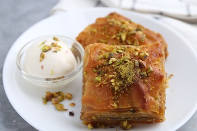 Photo of Tasty baklava with chopped nuts and scoop of ice cream on table, closeup