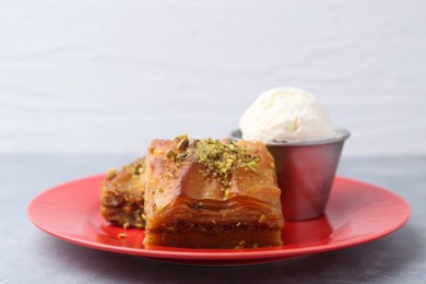 Photo of Tasty baklava with chopped nuts and scoop of ice cream on grey table, closeup