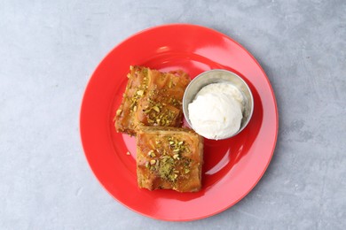 Photo of Tasty baklava with chopped nuts and scoop of ice cream on grey table, top view