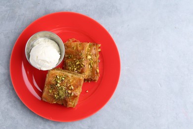 Photo of Tasty baklava with chopped nuts and scoop of ice cream on grey table, top view. Space for text