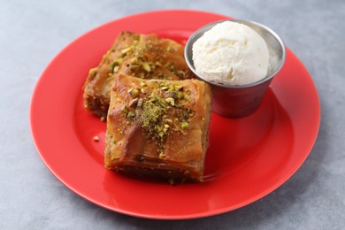 Photo of Tasty baklava with chopped nuts and scoop of ice cream on grey table, closeup